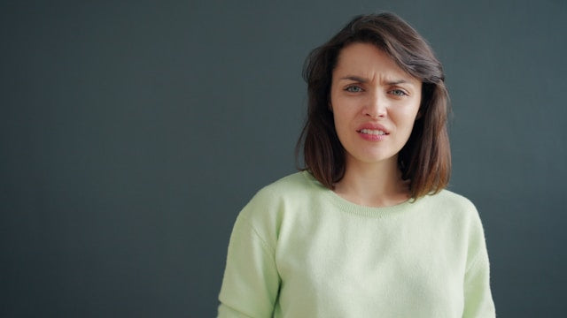 暗い背景に嫌な表情を浮かべた女性