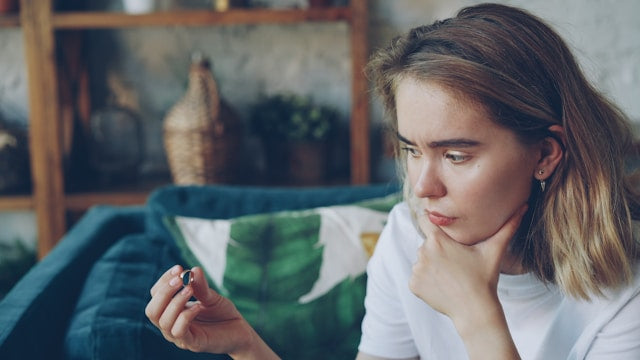 手に持った小さな物体を見つめる若い女性